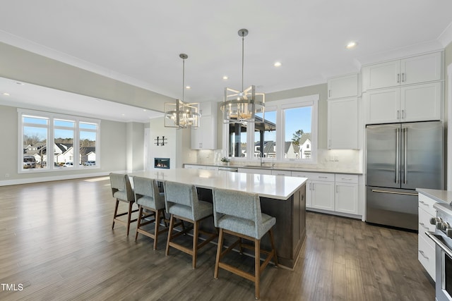 kitchen with a center island, white cabinets, hanging light fixtures, decorative backsplash, and stainless steel appliances