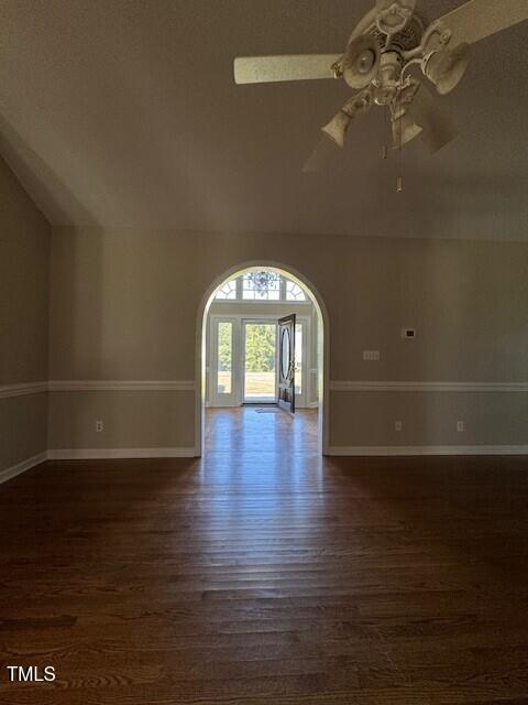 empty room featuring ceiling fan, dark wood-type flooring, and lofted ceiling