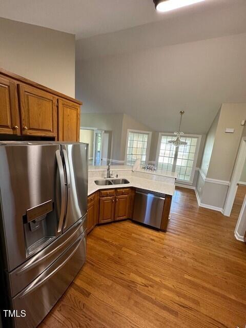 kitchen featuring hanging light fixtures, sink, light hardwood / wood-style flooring, appliances with stainless steel finishes, and kitchen peninsula