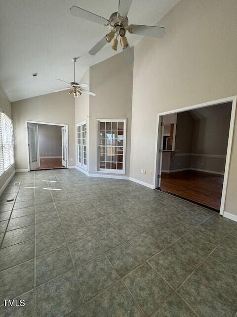 unfurnished living room featuring ceiling fan, high vaulted ceiling, and dark tile patterned flooring