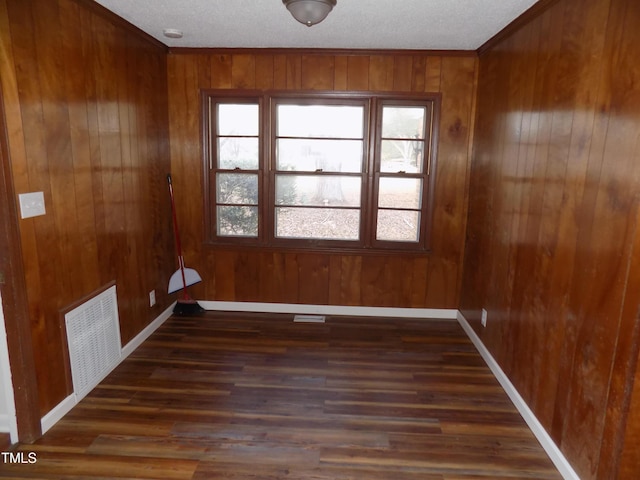 unfurnished room featuring wooden walls, crown molding, and dark wood-type flooring