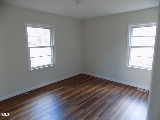 unfurnished room with plenty of natural light and dark wood-type flooring