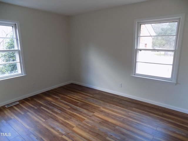 unfurnished room with plenty of natural light and dark wood-type flooring