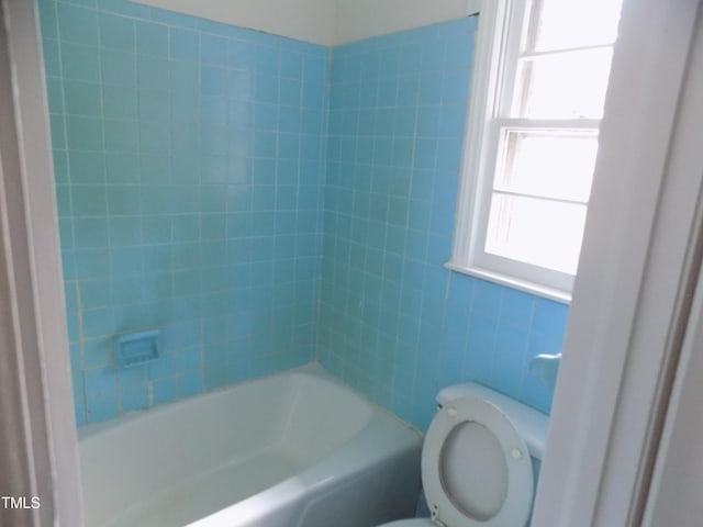 bathroom featuring tiled shower / bath combo and toilet