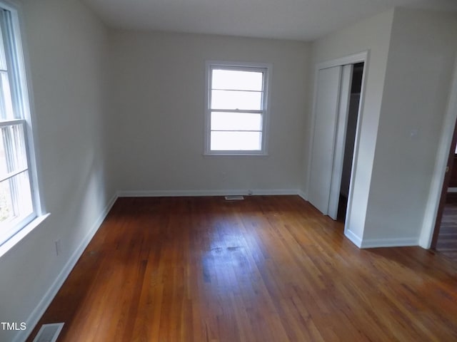 unfurnished bedroom with a closet and dark wood-type flooring