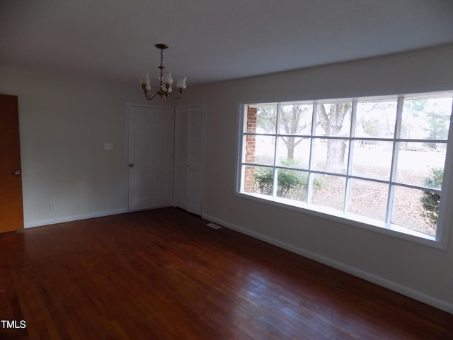 spare room featuring a chandelier and dark hardwood / wood-style floors