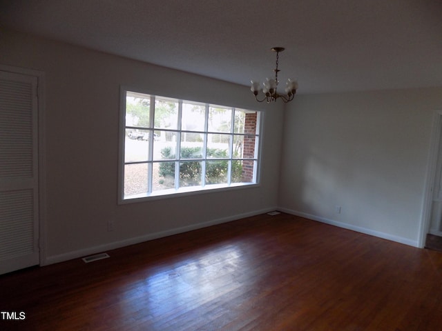 empty room featuring dark hardwood / wood-style floors and a notable chandelier