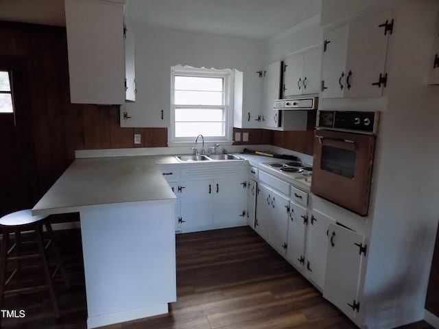 kitchen featuring dark wood-type flooring, white cabinets, sink, range hood, and black oven