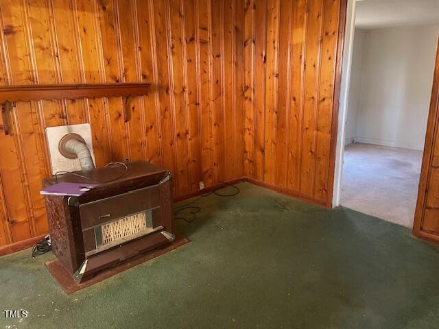 unfurnished living room with wooden walls and dark colored carpet