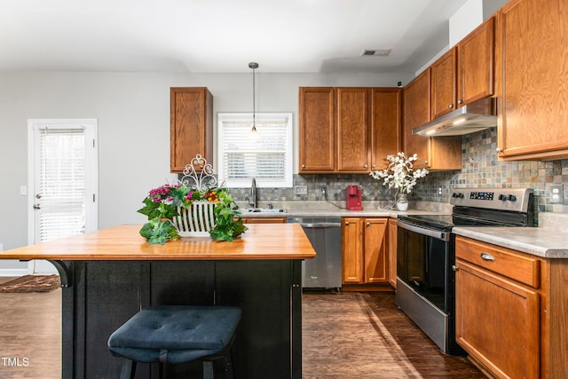 kitchen featuring pendant lighting, sink, dark hardwood / wood-style floors, appliances with stainless steel finishes, and tasteful backsplash