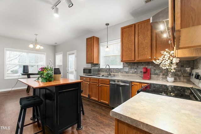 kitchen with a kitchen breakfast bar, plenty of natural light, stainless steel appliances, and decorative light fixtures