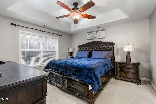 carpeted bedroom with a tray ceiling and ceiling fan