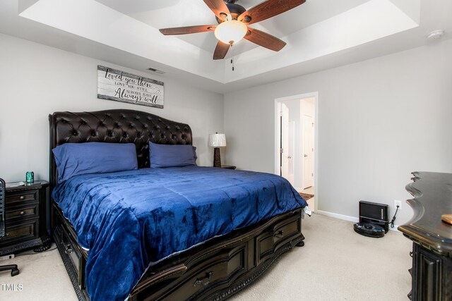 carpeted bedroom with ceiling fan and a tray ceiling