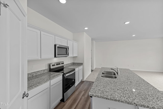 kitchen with white cabinets, a center island with sink, sink, dark hardwood / wood-style flooring, and stainless steel appliances