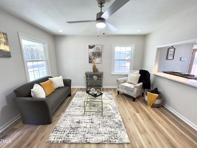 living room with wood-type flooring, a textured ceiling, a wealth of natural light, and ceiling fan