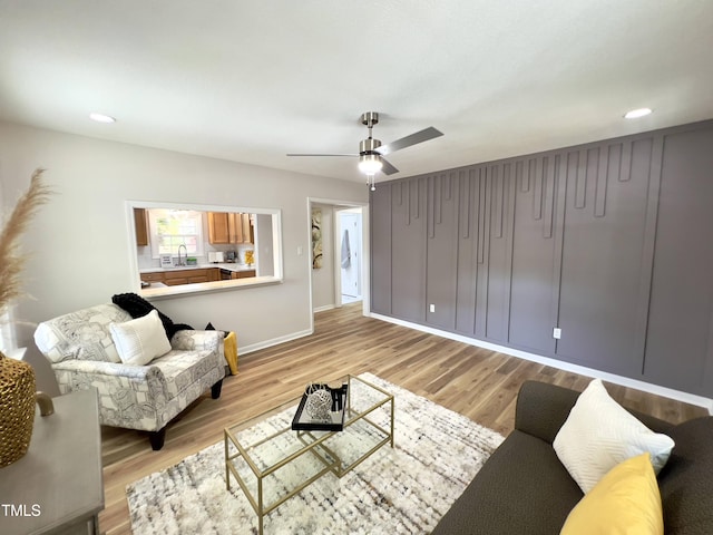 living room featuring ceiling fan, sink, and light hardwood / wood-style flooring