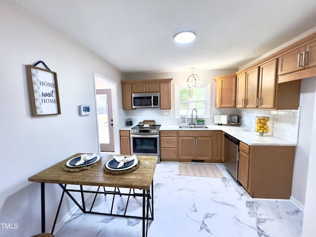 kitchen featuring backsplash, stainless steel appliances, hanging light fixtures, and sink