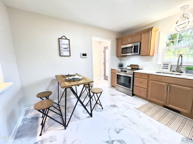 kitchen featuring tasteful backsplash, sink, hanging light fixtures, and appliances with stainless steel finishes