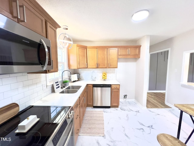 kitchen with backsplash, hanging light fixtures, sink, and appliances with stainless steel finishes