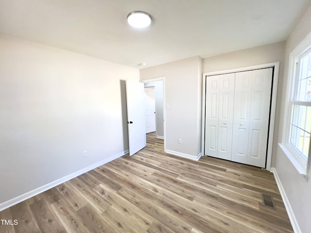 unfurnished bedroom with light hardwood / wood-style flooring and a closet