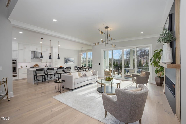 living room featuring ornamental molding, light hardwood / wood-style flooring, and a notable chandelier