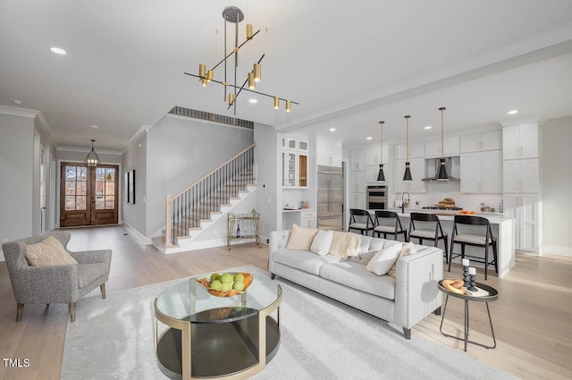 living room with light wood-type flooring, crown molding, french doors, and sink