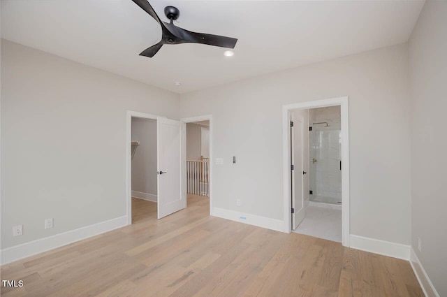 unfurnished bedroom featuring a spacious closet, ensuite bathroom, light hardwood / wood-style floors, ceiling fan, and a closet