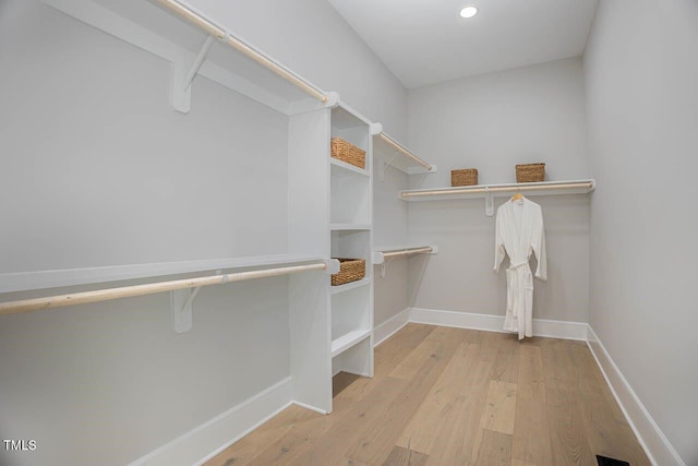 walk in closet with light hardwood / wood-style floors