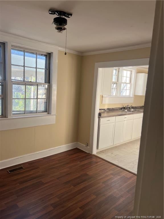 unfurnished dining area with sink, crown molding, and dark wood-type flooring