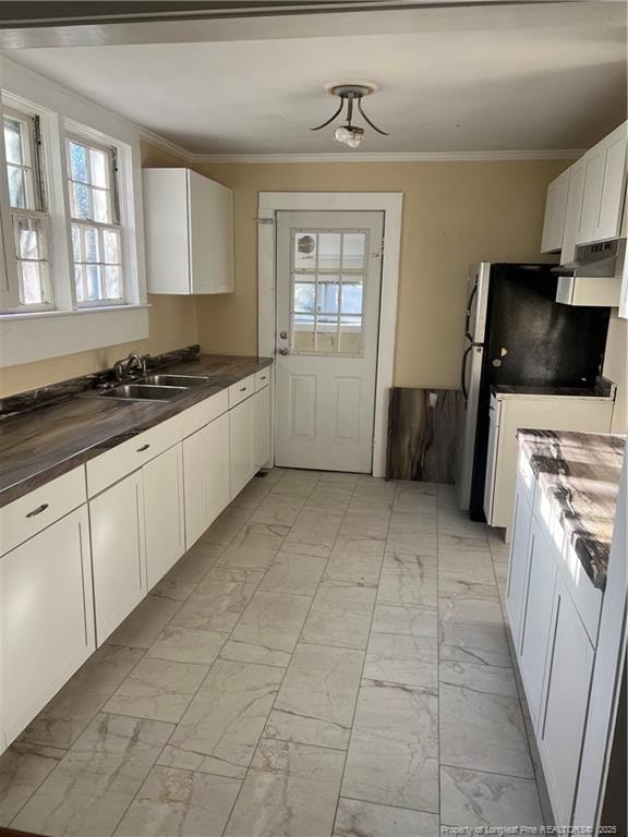 kitchen with refrigerator, white cabinetry, ornamental molding, and sink