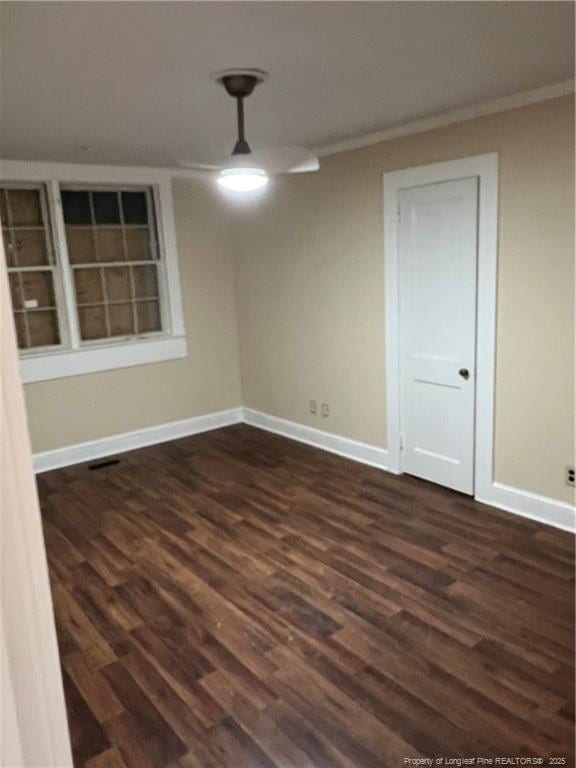 empty room featuring dark hardwood / wood-style floors and crown molding