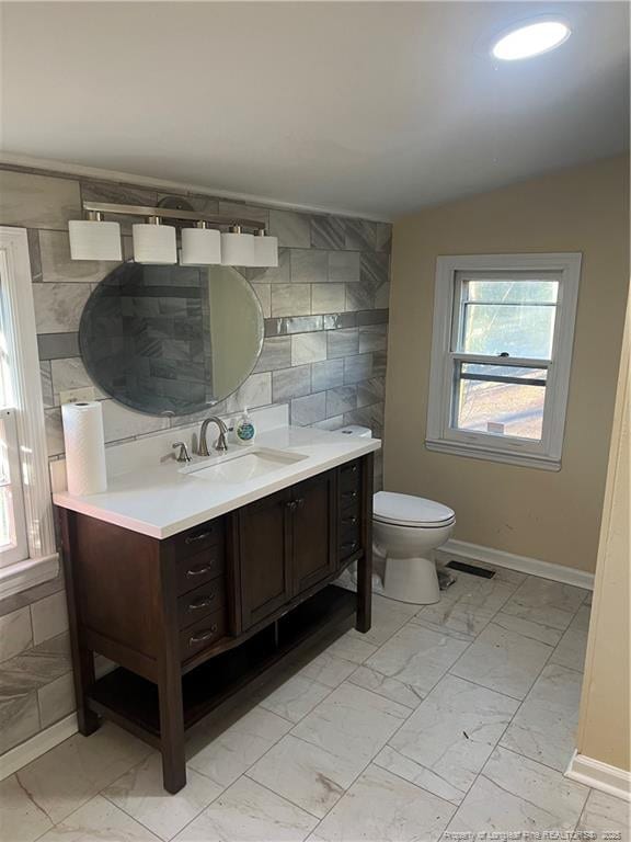 bathroom with vanity, toilet, and tile walls