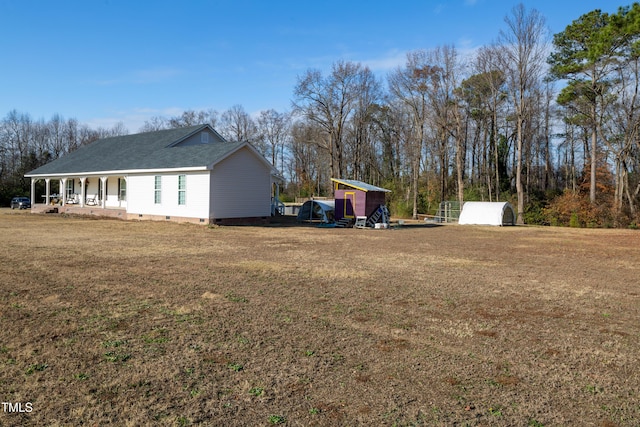 view of property exterior featuring a yard, covered porch, and a storage unit