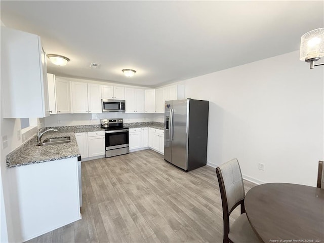 kitchen with stainless steel appliances, sink, stone counters, light hardwood / wood-style floors, and white cabinetry