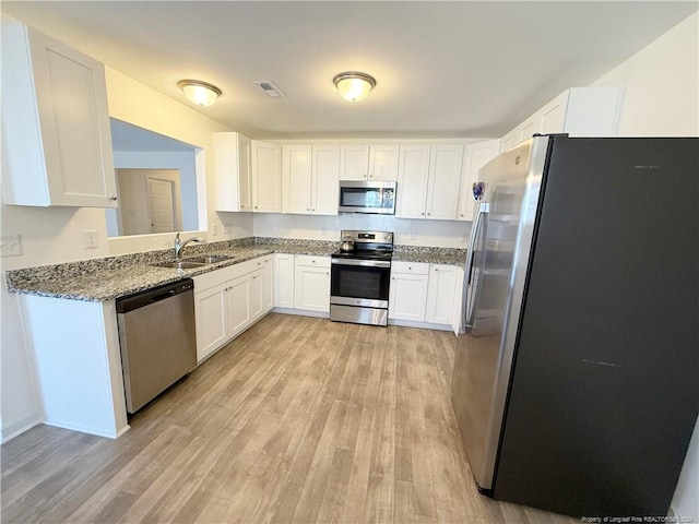 kitchen with sink, white cabinets, light wood-type flooring, and appliances with stainless steel finishes