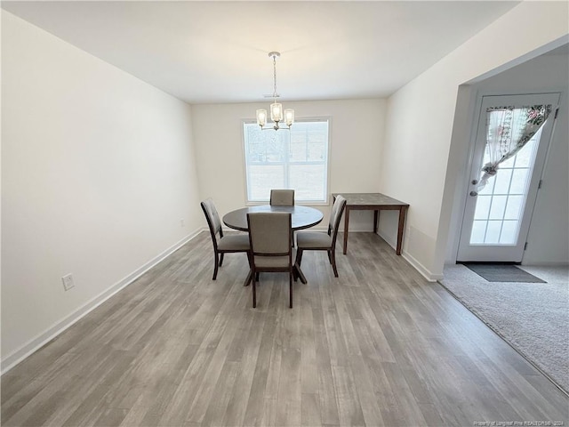 dining area with light hardwood / wood-style flooring and a chandelier