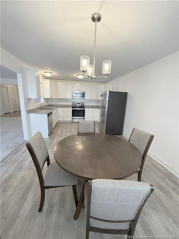 dining room with sink, light hardwood / wood-style floors, and an inviting chandelier