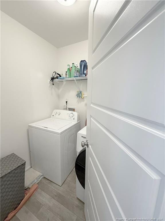 clothes washing area with washer / dryer and light hardwood / wood-style flooring