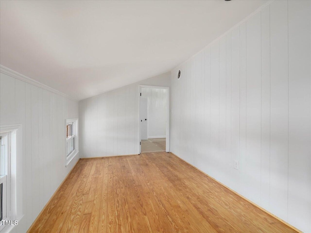 empty room featuring wood walls, light hardwood / wood-style floors, and lofted ceiling