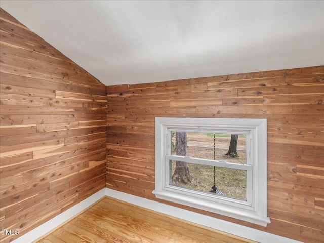 spare room featuring wooden walls, hardwood / wood-style floors, and lofted ceiling