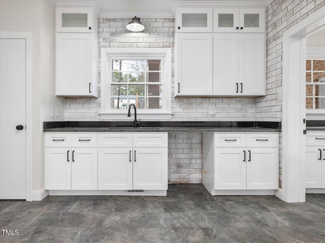 kitchen featuring tasteful backsplash, sink, white cabinets, and ornamental molding