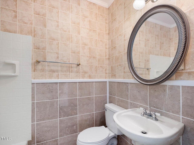 bathroom with toilet, sink, and tile walls