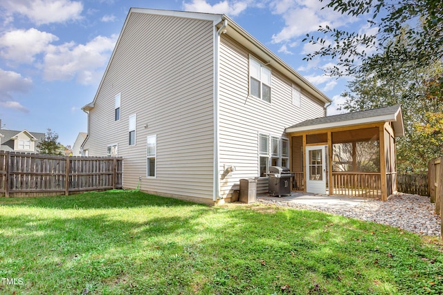 back of house featuring a sunroom, a patio area, and a lawn