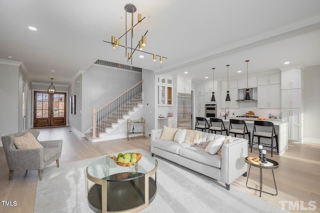 living room with french doors, light hardwood / wood-style floors, ornamental molding, and sink