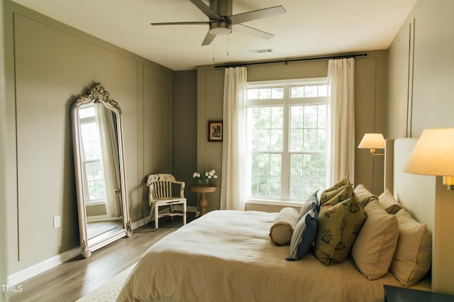 bedroom with hardwood / wood-style flooring, ceiling fan, and multiple windows