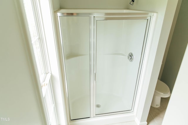 bathroom with tile patterned floors, toilet, and an enclosed shower