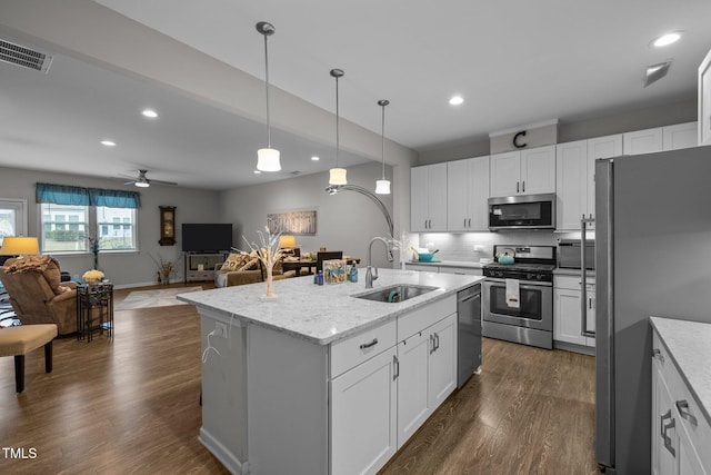 kitchen with light stone countertops, white cabinetry, stainless steel appliances, sink, and a center island with sink