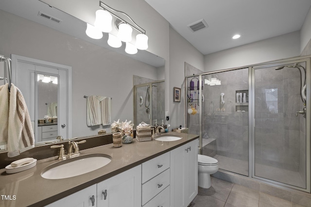 bathroom featuring a shower with shower door, toilet, vanity, and tile patterned flooring