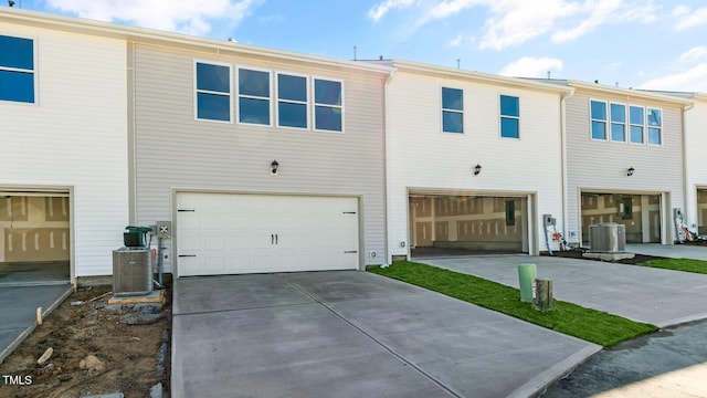 rear view of house featuring central AC unit and a garage