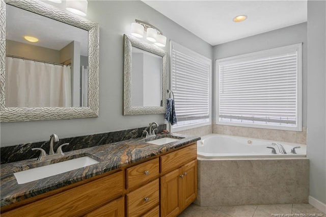 bathroom featuring tile patterned floors, vanity, and tiled bath